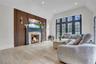 Living area with wood finished floors, a glass covered fireplace, vaulted ceiling, and recessed lighting
