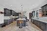 Kitchen featuring glass insert cabinets, backsplash, decorative light fixtures, a center island, and crown molding