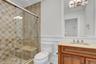 Full bath featuring a chandelier, crown molding, vanity, and a stall shower