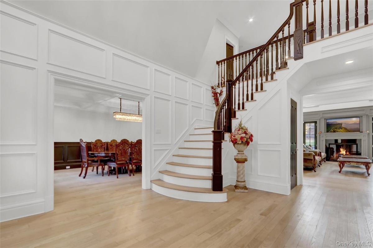 Staircase featuring a decorative wall, hardwood / wood-style floors, a towering ceiling, and a warm lit fireplace