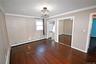 Unfurnished bedroom with two closets, dark wood-type flooring, ornamental molding, and a baseboard heating unit