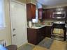 Kitchen featuring stainless steel appliances, decorative backsplash, light tile patterned floors, radiator heating unit, and light stone counters