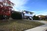 Split level home with brick siding, driveway, a front lawn, and an attached garage