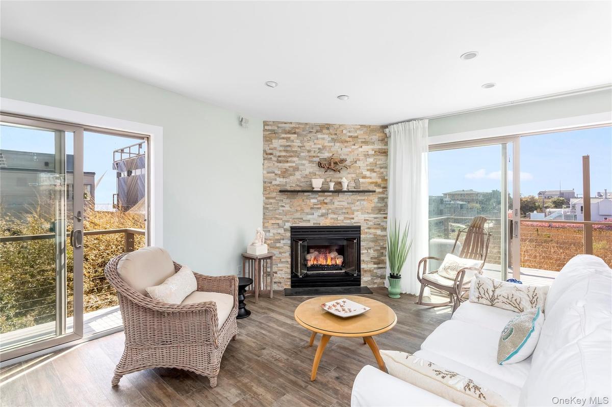Living area with wood finished floors, a stone fireplace, and recessed lighting