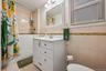 Full bath with tile walls, vanity, shower / bath combo, and light tile patterned floors