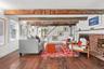 Living room with beam ceiling, a brick fireplace, and wood finished floors