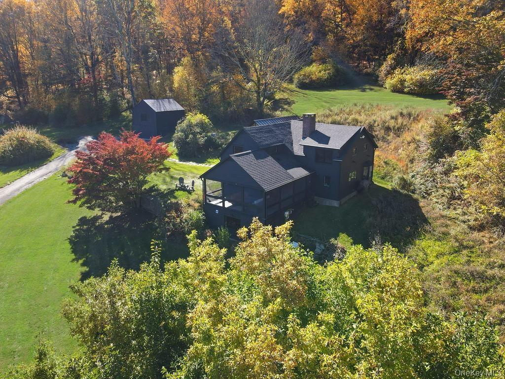 Aerial view of property and surrounding area with a forest