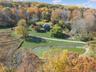 Aerial view of property and surrounding area with a nearby body of water and a forest