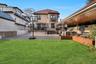 Rear view of property featuring a yard, a patio, a tile roof, and a balcony