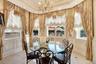 Dining space with a decorative wall, a chandelier, tile patterned flooring, crown molding, and a tray ceiling