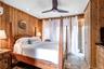 Bedroom featuring wood walls, ceiling fan, and dark stone finish flooring