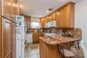 Kitchen featuring a peninsula, white appliances, decorative backsplash, recessed lighting, and brown cabinets