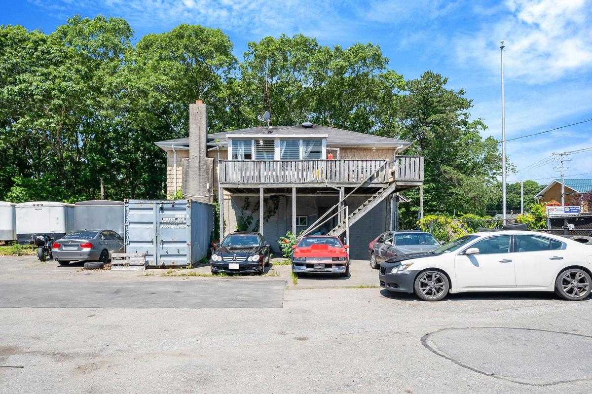 View of front of house with stairs, a wooden deck, uncovered parking, and a chimney