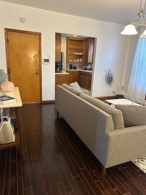 Living area featuring dark wood-style floors, baseboards, and a chandelier