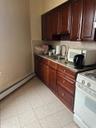 Kitchen featuring a sink, baseboard heating, range, light stone counters, and light tile patterned floors