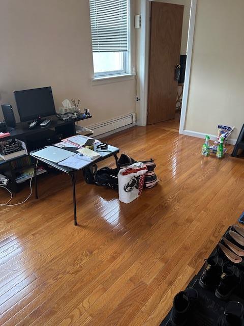 Home office with a baseboard radiator, hardwood / wood-style flooring, and baseboards