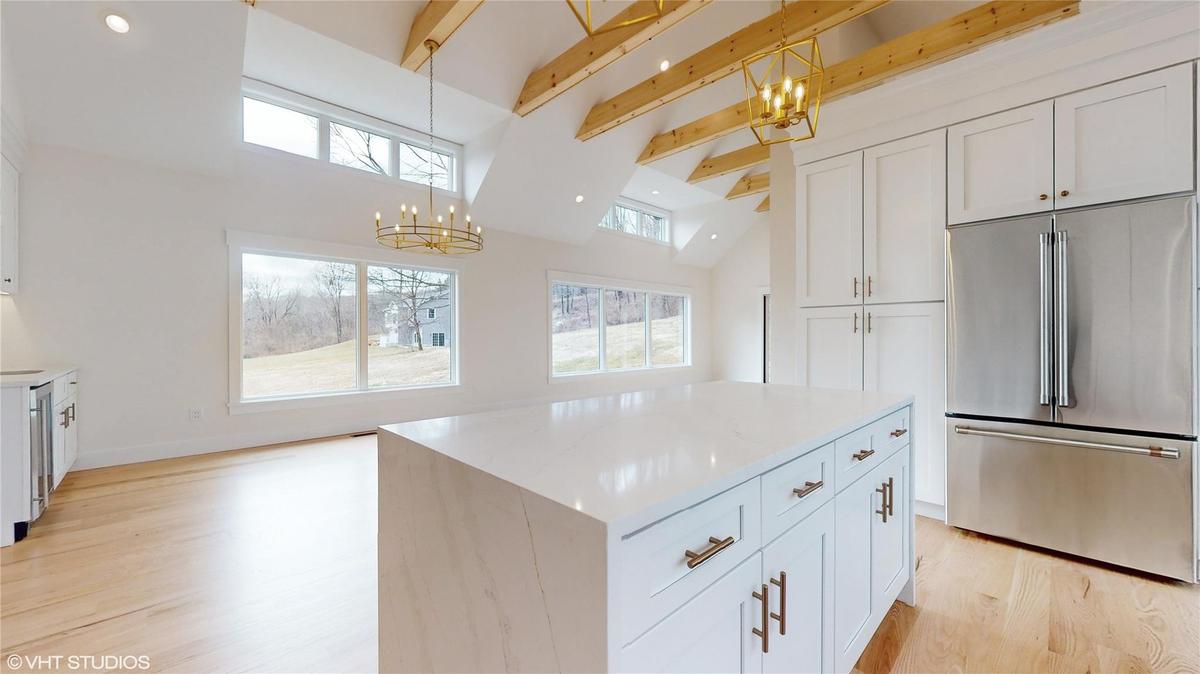 Kitchen with white cabinets, a center island, stainless steel appliances, and hanging light fixtures