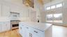 Kitchen featuring premium range hood, white cabinets, and stainless steel stove