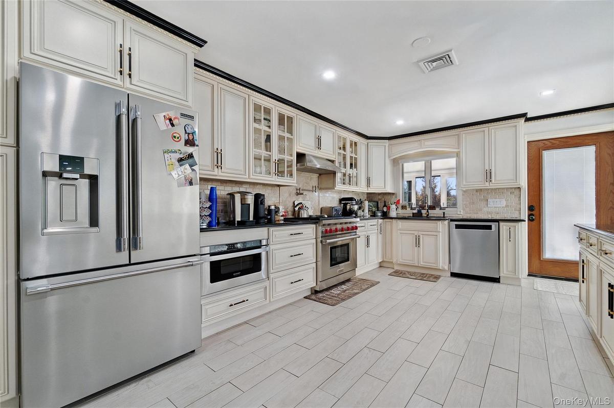 Kitchen featuring stainless steel appliances, tasteful backsplash, glass insert cabinets, recessed lighting, and light wood-style floors