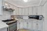 Kitchen with appliances with stainless steel finishes, tasteful backsplash, under cabinet range hood, light wood-style flooring, and ornamental moldin