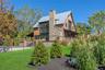 Rear view of property featuring a standing seam roof, a metal roof, a yard, a chimney, and stone siding