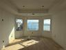 Spare room featuring a tray ceiling, wood finished floors, and ornamental molding