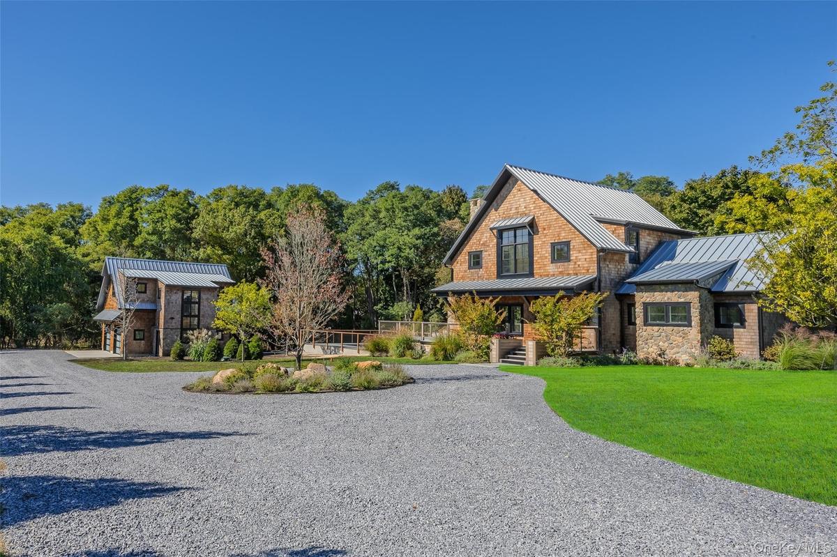 View of front of house featuring a standing seam roof, a metal roof, driveway, a porch, and a front lawn