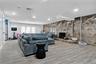 Living area with a stone fireplace, wood finished floors, tile walls, and recessed lighting