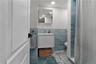 Full bath with tile walls, a shower with curtain, wainscoting, vanity, and light tile patterned flooring