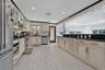 Kitchen featuring glass insert cabinets, stainless steel appliances, tasteful backsplash, cream cabinetry, and dark stone counters