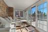 Sunroom / solarium featuring brick wall, vaulted ceiling, and wood finished floors