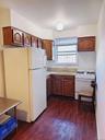 Kitchen featuring light countertops, white appliances, dark wood-type flooring, a sink, and brown cabinetry