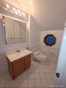 Bathroom featuring lofted ceiling, vanity, light tile patterned floors, and wainscoting