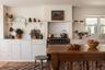 Kitchen with open shelves, white cabinetry, and black range
