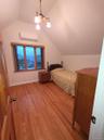 Bedroom featuring lofted ceiling, light wood-style floors, a wall mounted AC, and a chandelier