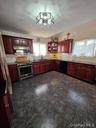Kitchen with reddish brown cabinets, appliances with stainless steel finishes, plenty of natural light, and backsplash
