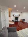 Living room featuring dark wood-style floors, a glass covered fireplace, and recessed lighting