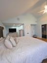 Bedroom featuring a ceiling fan, high vaulted ceiling, and wood finished floors