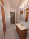 Bathroom with vanity, a shower stall, light tile patterned floors, wainscoting, and lofted ceiling