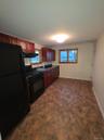 Kitchen featuring black appliances, dark countertops, under cabinet range hood, dark brown cabinets, and stone finish flooring