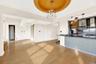Kitchen with tasteful backsplash, pendant lighting, wall chimney exhaust hood, open floor plan, and dark stone counters