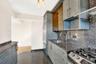 Kitchen featuring granite floors, stainless steel appliances, backsplash, open shelves, and dark stone countertops