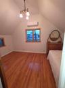 Unfurnished bedroom with light wood-style floors, lofted ceiling, a wall mounted AC, and a chandelier