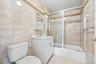 Full bathroom featuring toilet, tile walls, vanity, and enclosed tub / shower combo