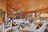 Living room featuring wooden walls, high vaulted ceiling, wood ceiling, a chandelier, and a wood stove