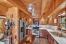 Kitchen featuring stainless steel appliances, brown cabinets, glass insert cabinets, wood walls, and dark stone finish flooring