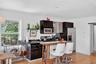 Kitchen with light wood-style flooring, a breakfast bar area, appliances with stainless steel finishes, recessed lighting, and dark cabinets