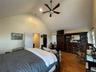 Bedroom featuring a spacious closet, wood finished floors, high vaulted ceiling, and a ceiling fan