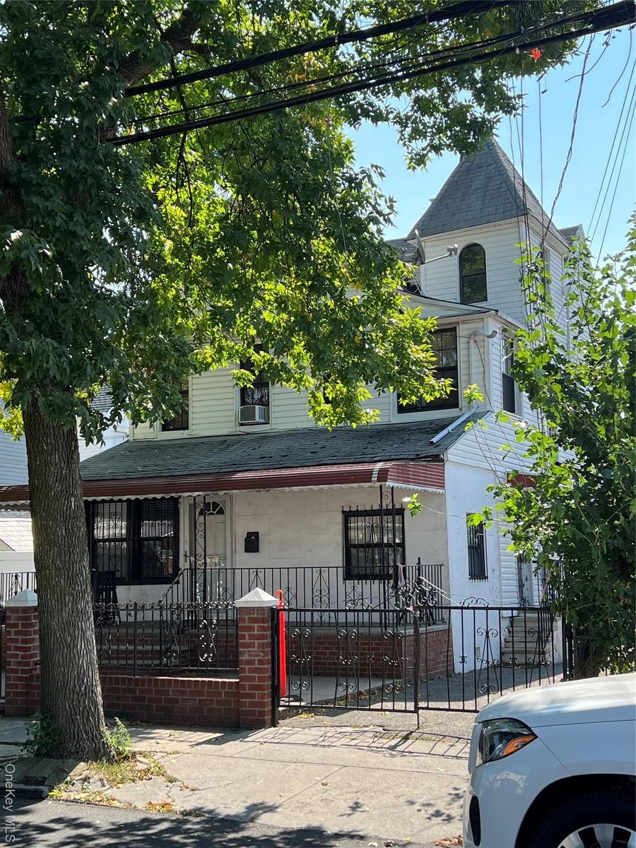 View of front of home with a shingled roof, a fenced front yard, a gate, and covered porch
