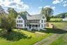 Colonial home featuring covered porch, a chimney, a front lawn, and roof with shingles